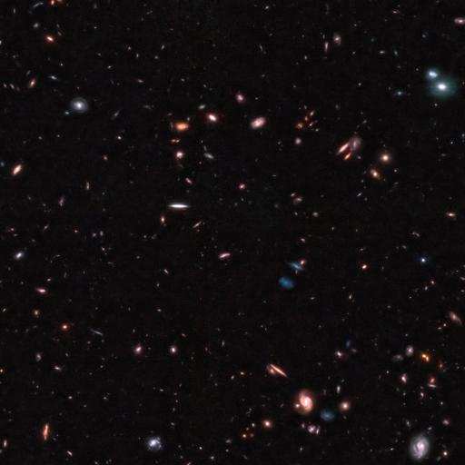 A deep-space image captured by the JWST showcases numerous galaxies of various shapes, sizes, and colors scattered across a dark background, potentially setting a new cosmic distance record.