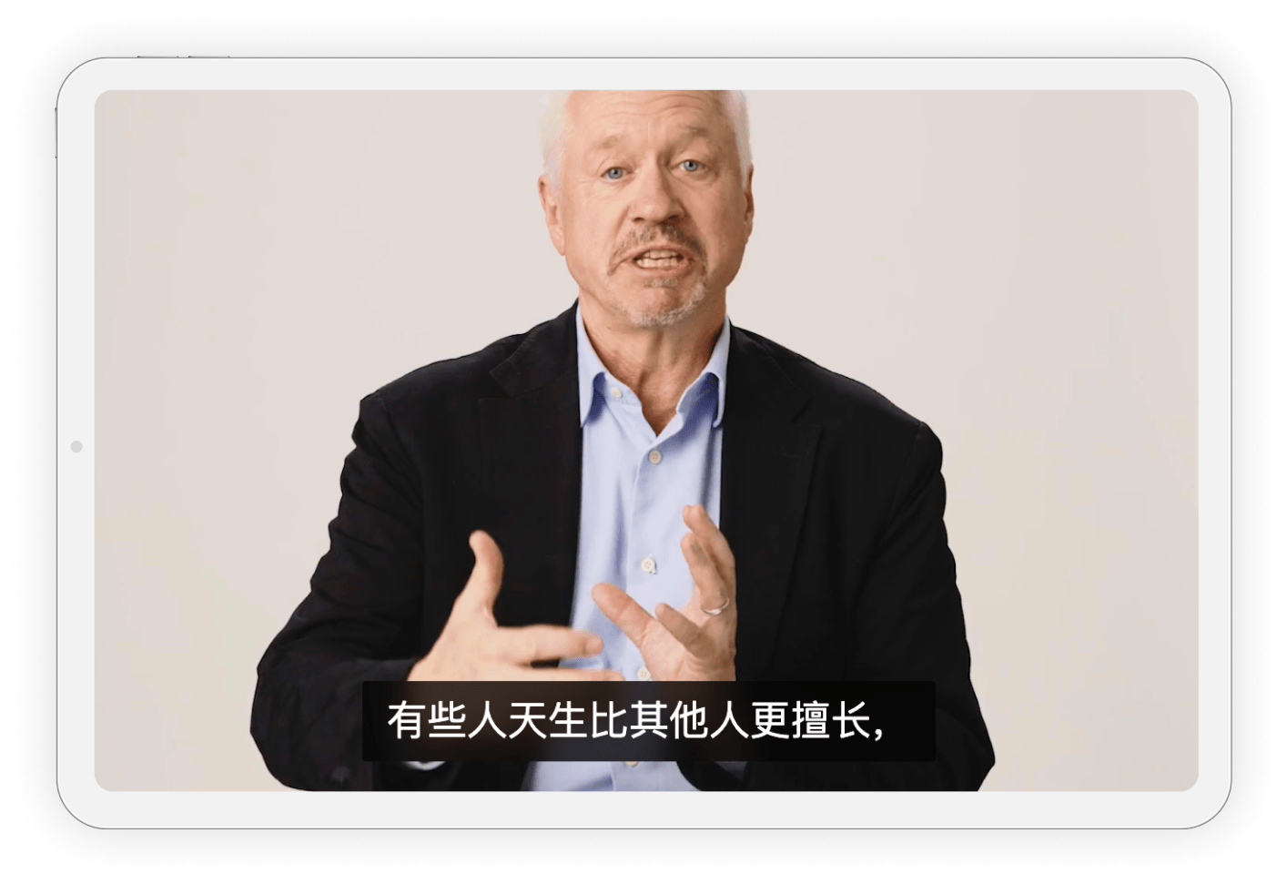A man in a suit gestures while speaking, with Chinese subtitles displayed on the screen.