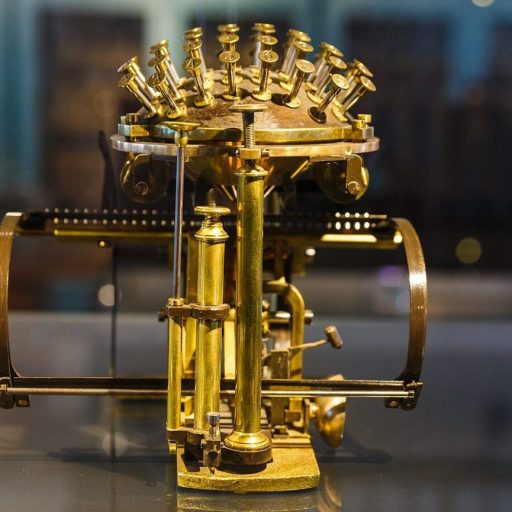 A vintage brass typewriter with exposed keys and mechanisms, evoking a sense of typing consciousness, displayed on a reflective surface.