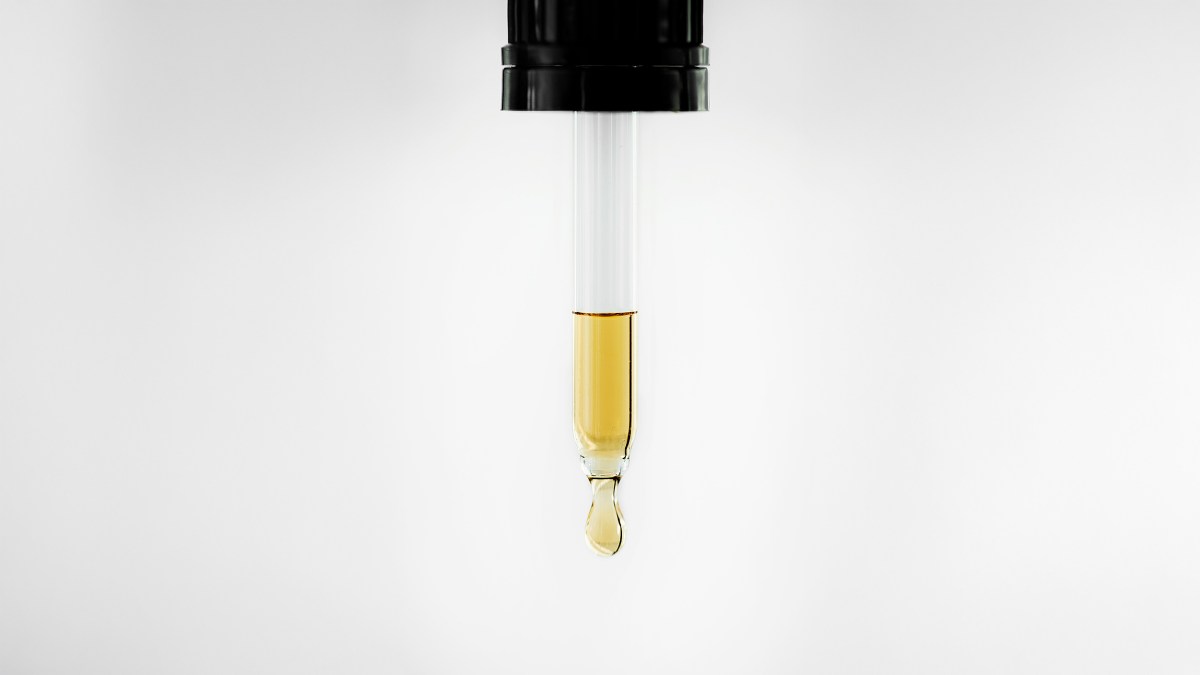 Close-up of a dropper releasing a drop of yellow liquid, showcasing the foundation of chemistry against a pristine white background.
