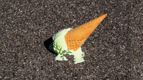 A hint of pessimism drips from the upside-down mint ice cream cone melting on the asphalt, a sweet reminder that some delights are meant to slip away.