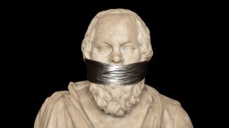 Marble bust of a bearded man with eyes closed and mouth covered by a strip of black tape, set against a black background.