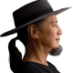 A man with a black ponytail and goatee wearing a wide-brimmed hat and black shirt is shown in profile against a dark background.
