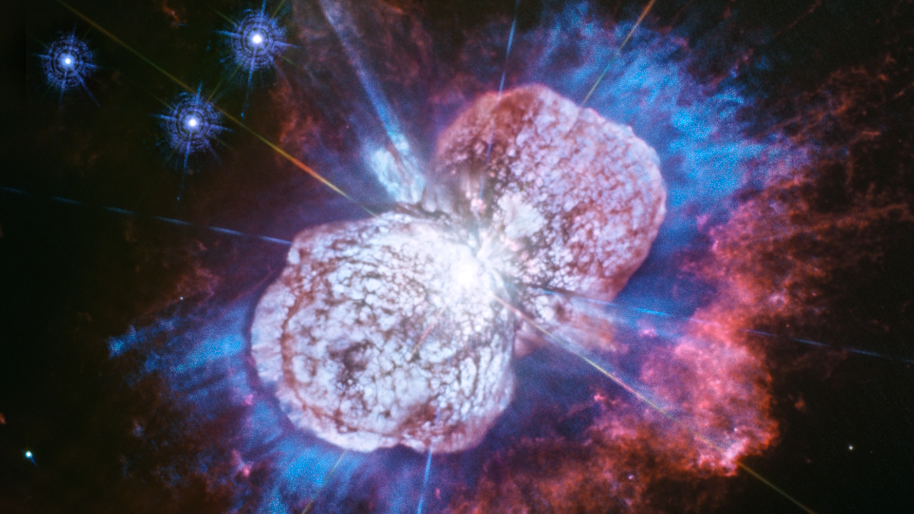 Two bright, irregularly shaped nebula clouds with blue, purple, and pink gases dominate the dark space background, where dazzling stars twinkle—reminding us that in space, appearances can deceive.