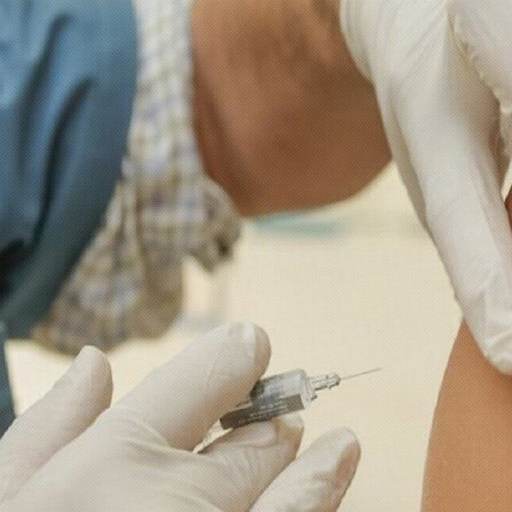A healthcare worker wearing gloves administers an injection with a syringe into a person's upper arm, reminding us that when it comes to vaccines, do your own research and stay informed.
