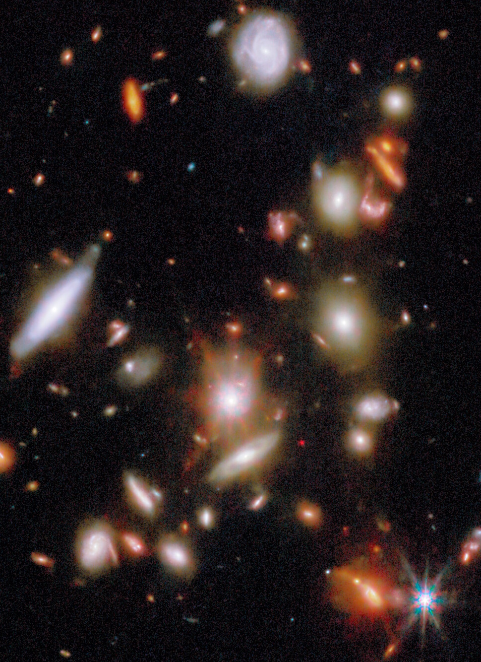 A cluster of colorful galaxies and stars scattered across a dark space background, captured by a telescope.
