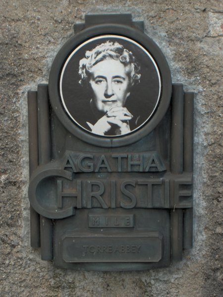 A metal plaque with a portrait of Agatha Christie and text reading “Agatha Christie Mile, Torre Abbey.”.