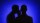 Two silhouetted figures against a blue background, with one appearing to whisper to the other.