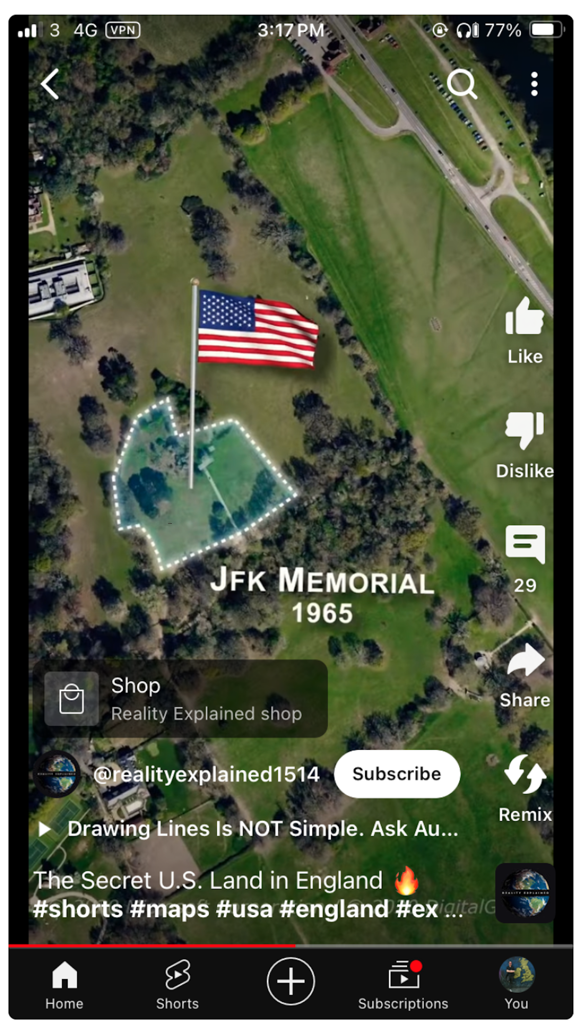 Aerial view of a grassy area labeled "Jfk Memorial 1965" with a large American flag, surrounded by trees and paths, shown on a mobile device screen.