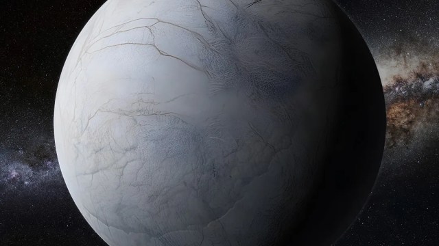 A grey, icy planet or moon with surface cracks is shown against a backdrop of stars and the Milky Way galaxy.