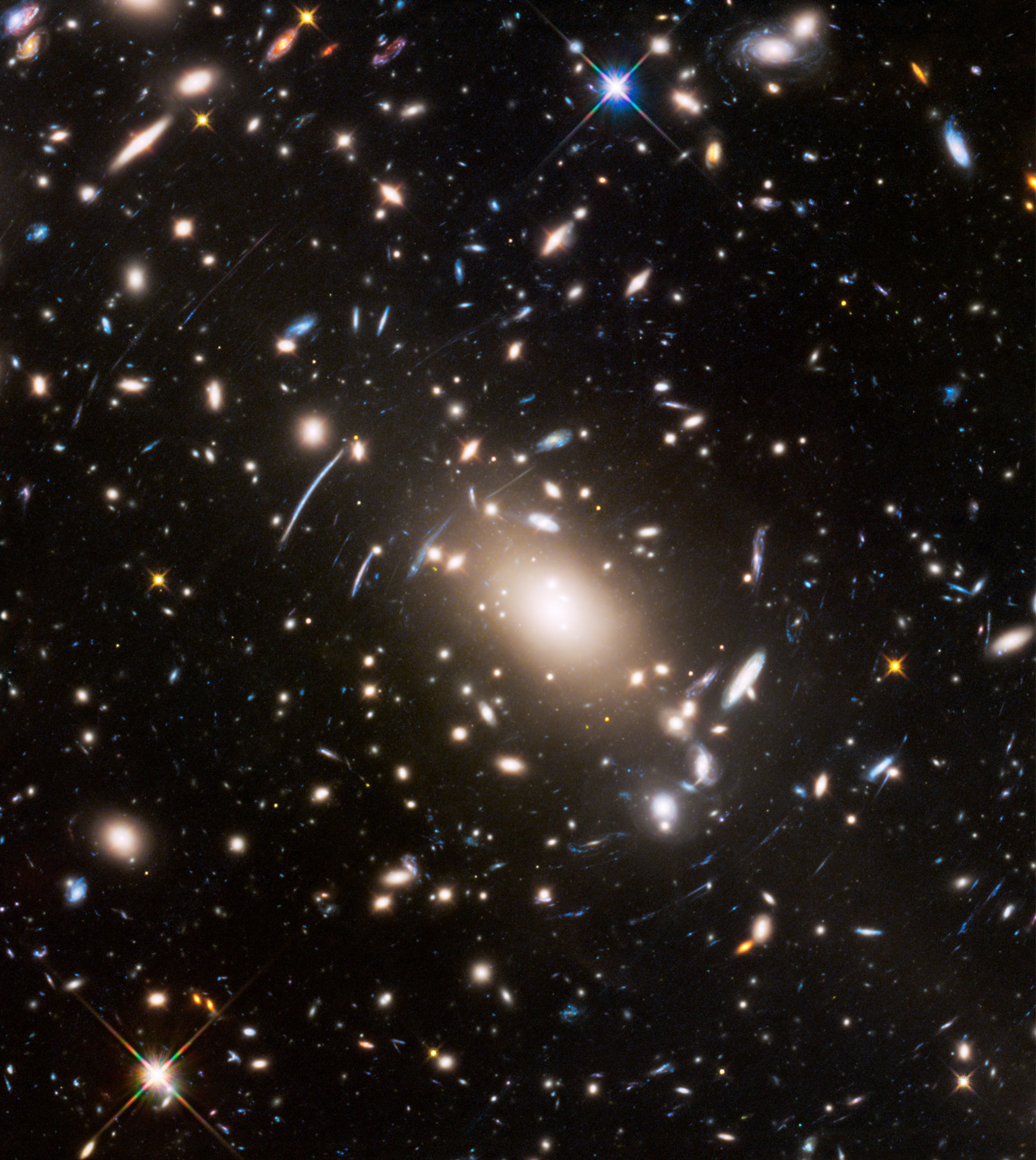 A dense galaxy cluster with numerous bright stars and elongated arcs caused by the JWST’s most extreme gravitational lens, set against a dark background in deep space.