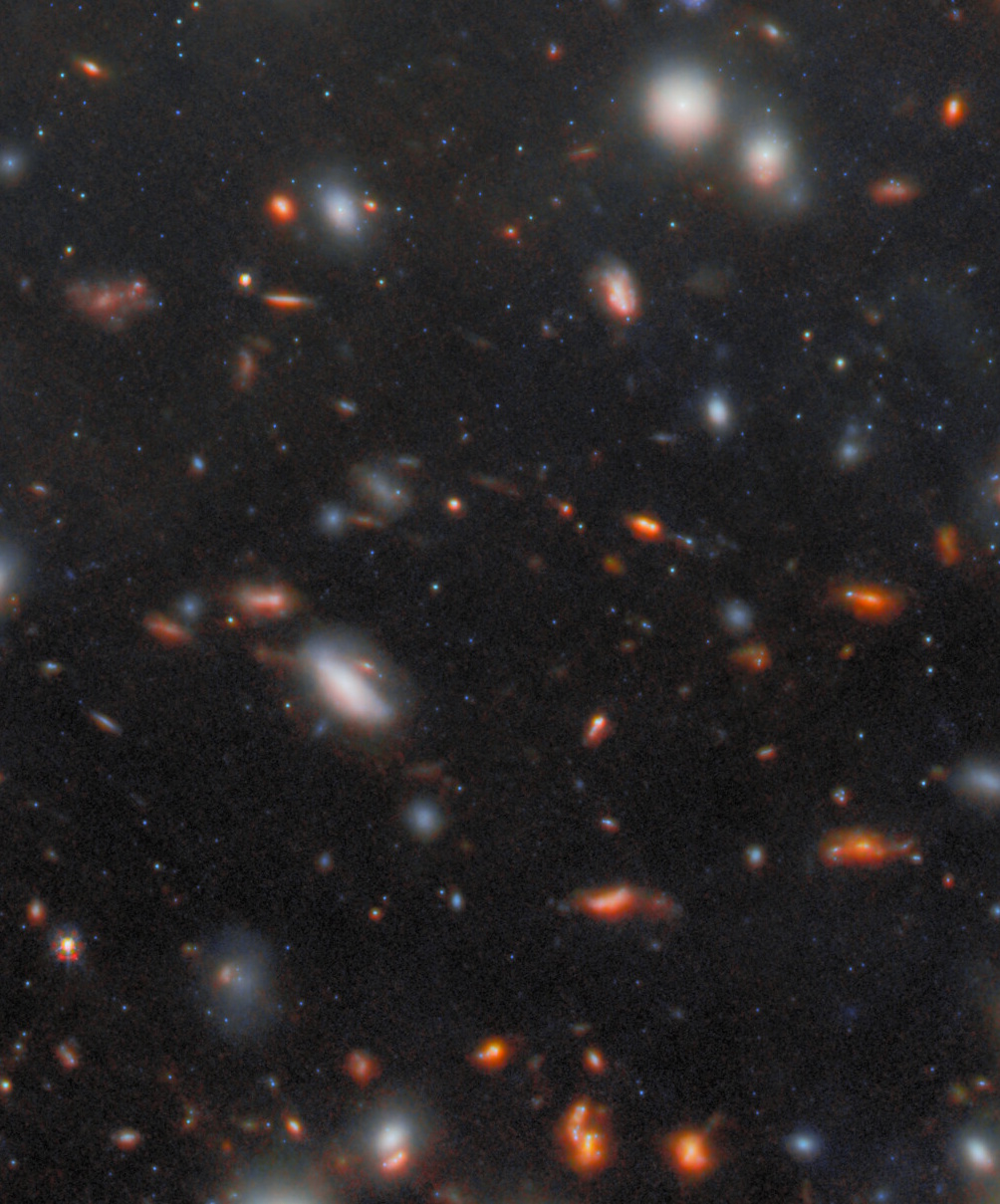 A field of distant galaxies, revealed by JWST’s most extreme gravitational lens, showcases varying sizes and colors scattered across a dark space background, with numerous points of light and diffuse glows.