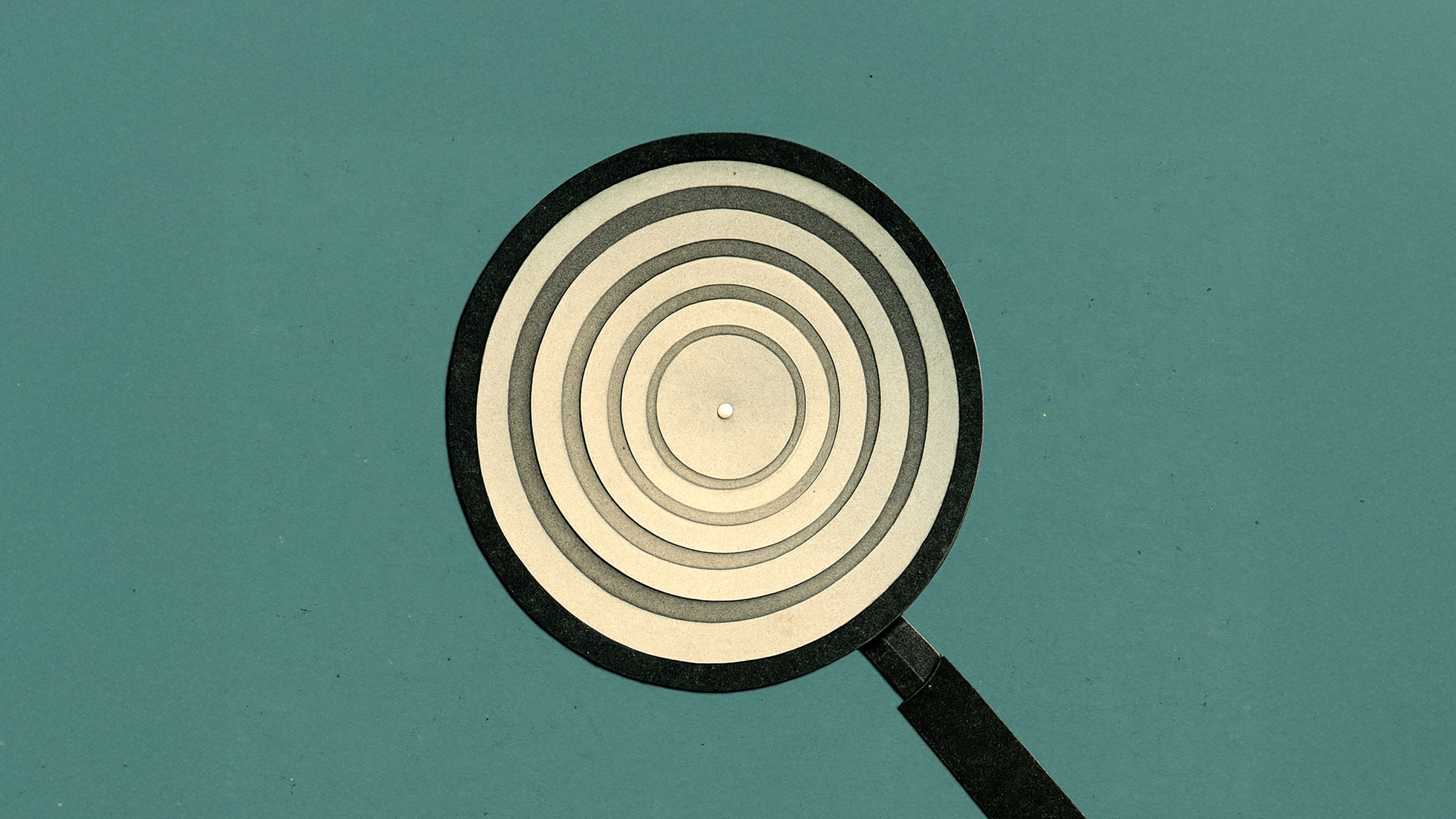 A magnifying glass focusing on concentric circles against a plain teal background.