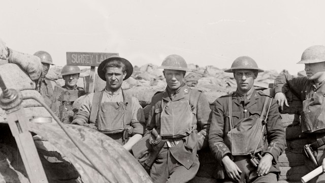 Five World War I soldiers in uniform stand and sit near sandbags in a trench, with a sign reading "Surrey Lane" visible in the background—evoking camaraderie amid the Ring of Fire on the front lines.