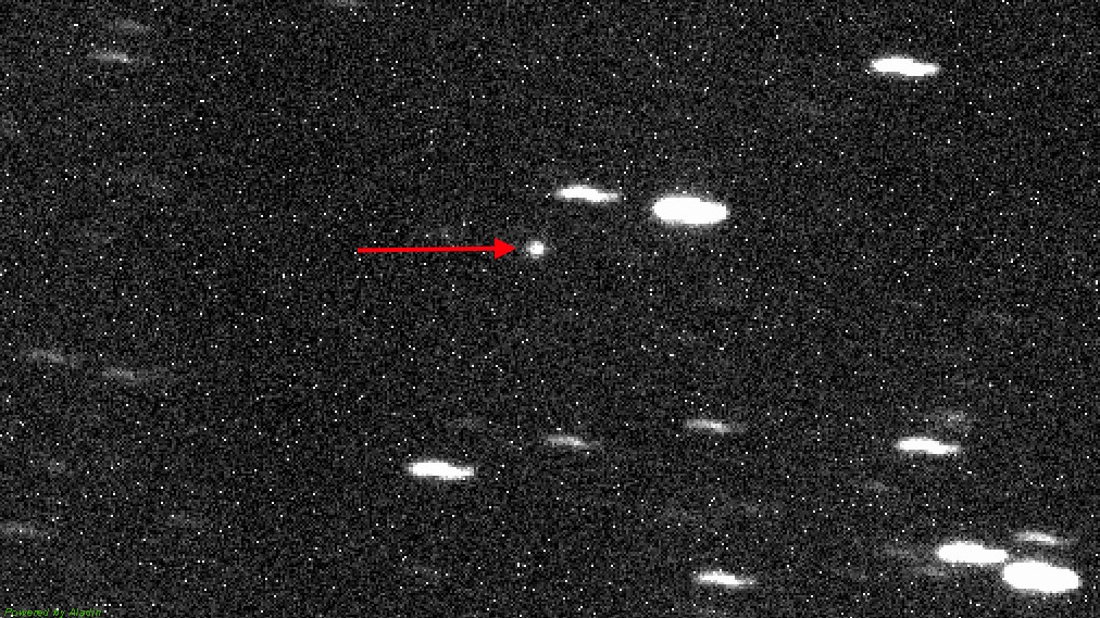 Black and white image of a star field with one bright object in the center, indicated by a red arrow, believed to be the third interstellar object detected passing through our solar system.