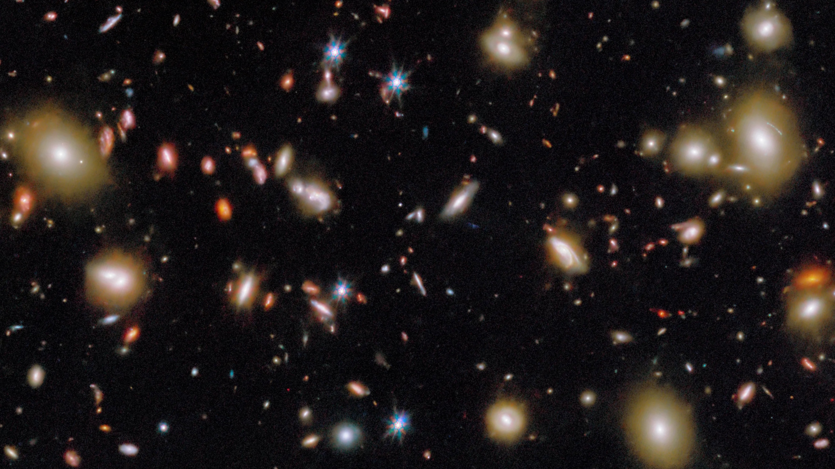 A dense field of distant galaxies and bright stars against a black background, as captured in a JWST early galaxies deep space telescope image.