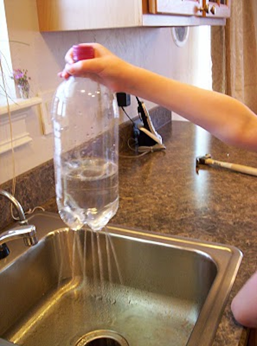 A hand holds a plastic bottle filled with water over a sink, with water streaming out of holes in the bottom—demonstrating how even scientists explore the possibility behind simple phenomena.