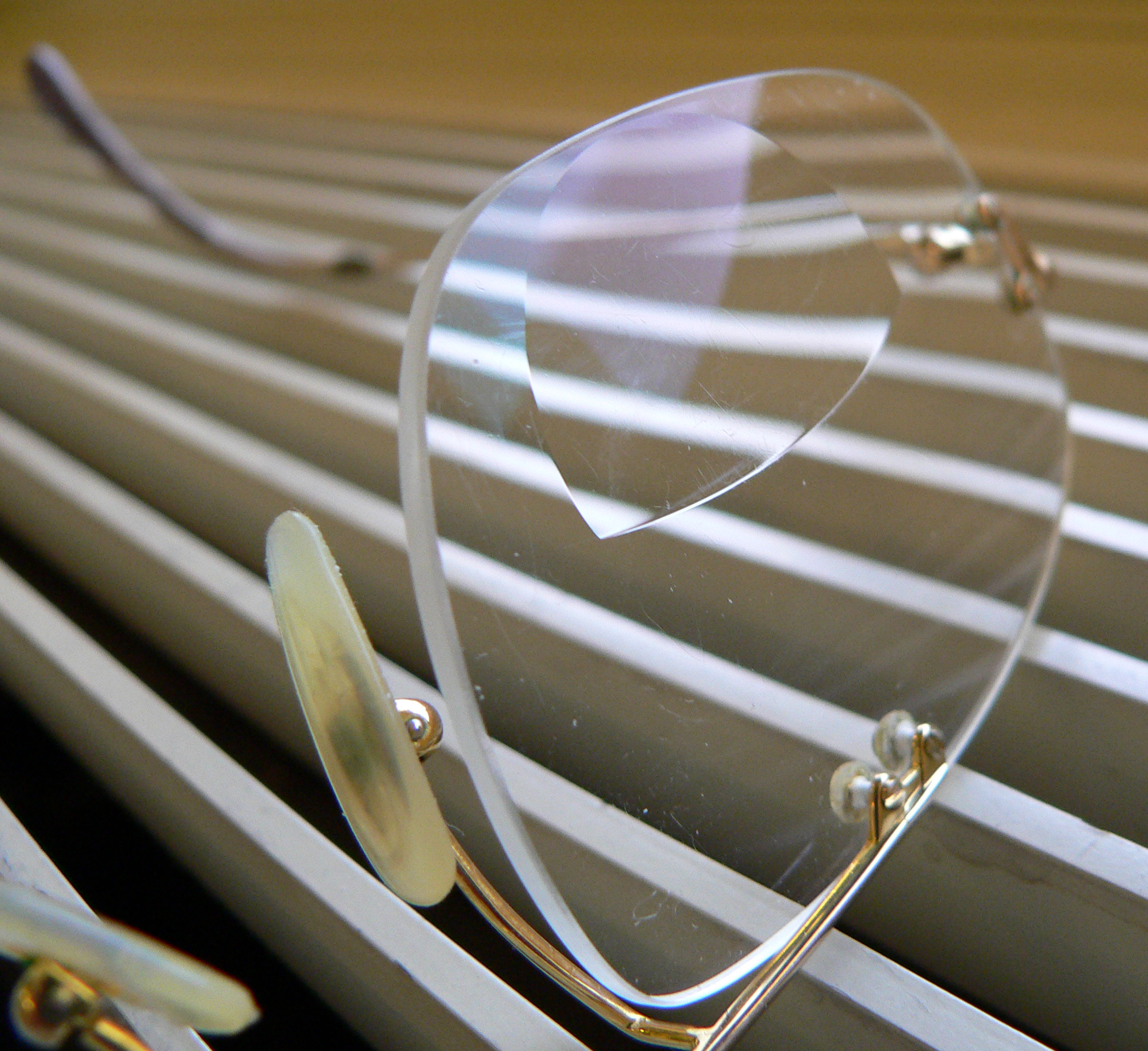 A pair of broken eyeglasses with one lens cracked, resting on metal slats—a reminder of how the science of LASIK offers freedom from such fragile dependence.