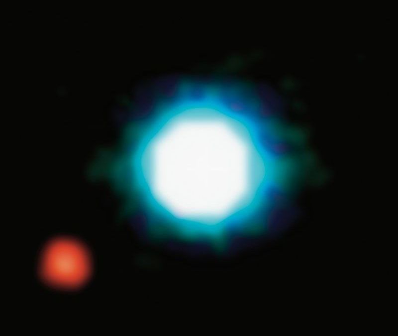 A bright, circular blue and white object is centered against a black background, with a smaller red object to the lower left.