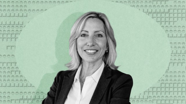 Susan Schneider, in a business suit, smiles at the camera, with a green patterned background behind her.