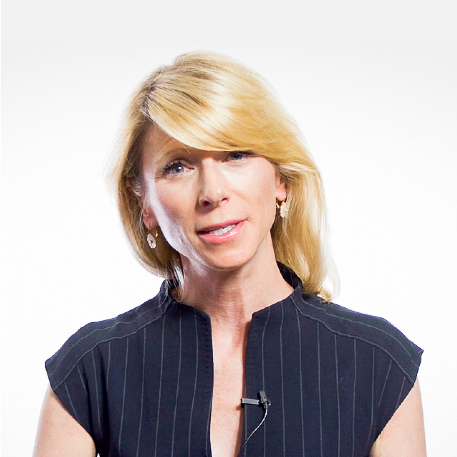 A woman with blonde hair, wearing a black, short-sleeved, pinstriped top and a lapel microphone, stands against a plain white background.