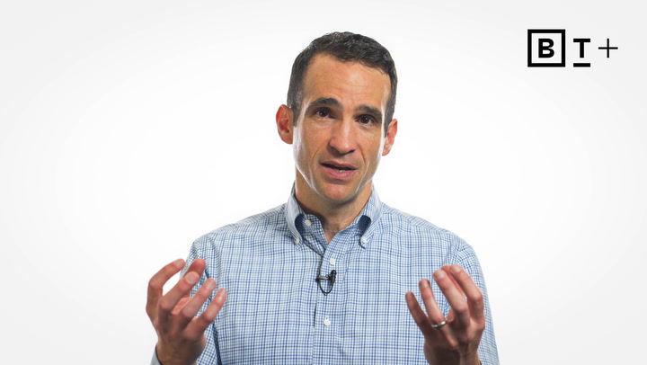 A man in a checked shirt speaks while gesturing with his hands. A BT+ logo is visible in the top right corner against a white background.