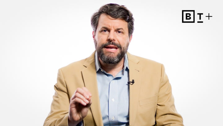 A man with a beard in a tan blazer and blue checkered shirt speaks while gesturing, against a plain white background with a "BT+" logo.
