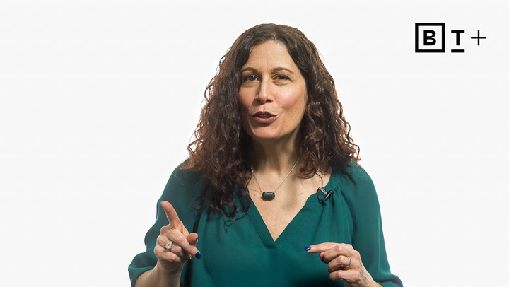 A woman with curly brown hair wearing a green top speaks while gesturing with her hands. A “BT+” logo appears in the top right corner.