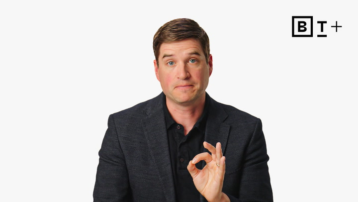A man in a dark blazer holds up his hand, making an "OK" gesture. A minimalist logo with the letters "B T +" appears in the top right corner.