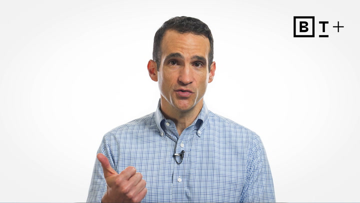 A man in a checked shirt speaks while gesturing with his left thumb up; a black and white “BT+” logo appears in the upper right corner.