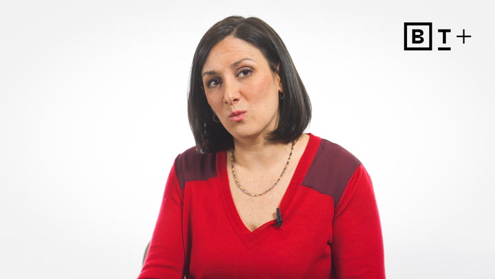 A woman with straight dark hair wearing a red sweater and necklace sits against a plain white background with a "B T +" logo in the corner.
