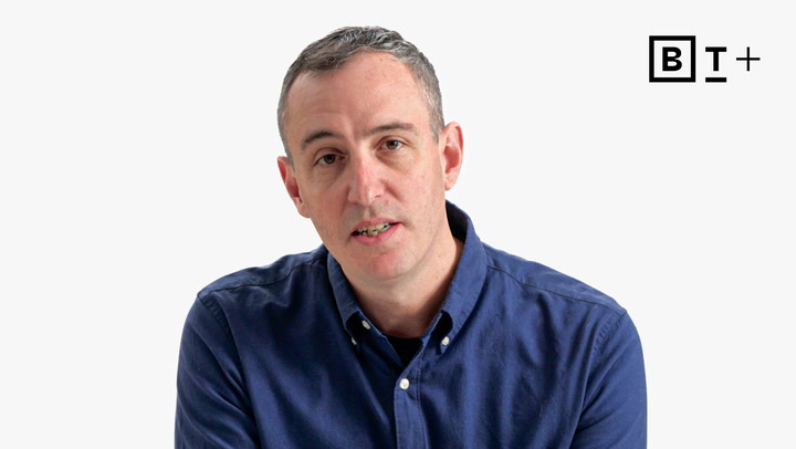 A man in a blue button-up shirt sits in front of a plain white background with a "BT+" logo in the top right corner.