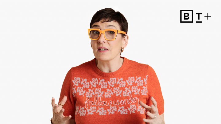 A person with short dark hair wears orange glasses and an orange shirt that says "follow wonder," gesturing with both hands. A "BT+" logo appears in the top right corner.
