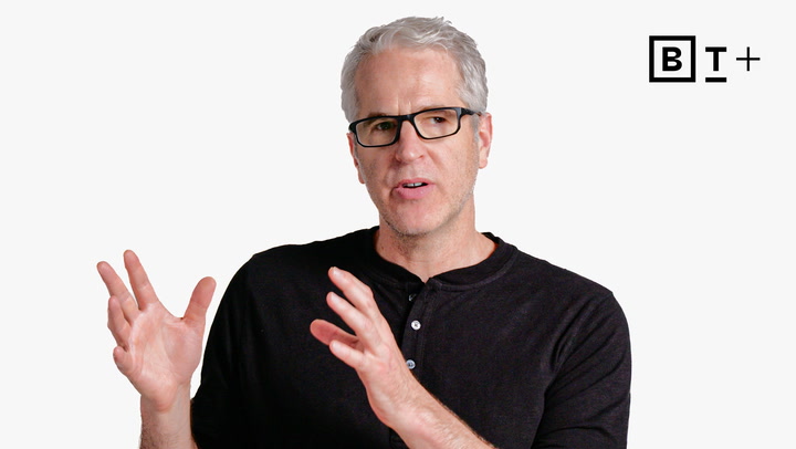 A man with gray hair and glasses, wearing a black shirt, gestures with his hands while speaking. The BT+ logo appears in the top right corner.