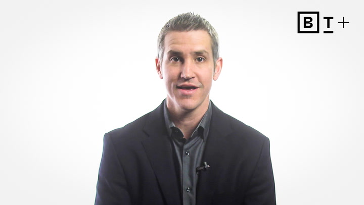 A man in a dark suit sits in front of a white background with the BT+ logo in the top right corner.