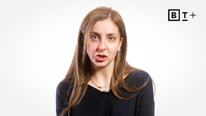 A woman with long brown hair wearing a black top speaks in front of a plain white background with the "B T +" logo in the top right corner.