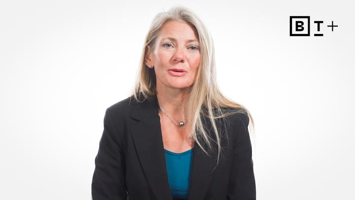 A woman with long blonde hair wearing a black blazer and teal top sits in front of a white background with a "BT+" logo in the top right corner.