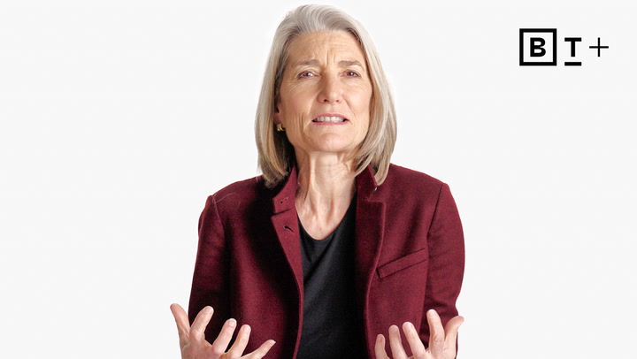 A person with gray hair in a maroon blazer and black shirt gestures with their hands; a "BT+" logo appears in the top right corner.