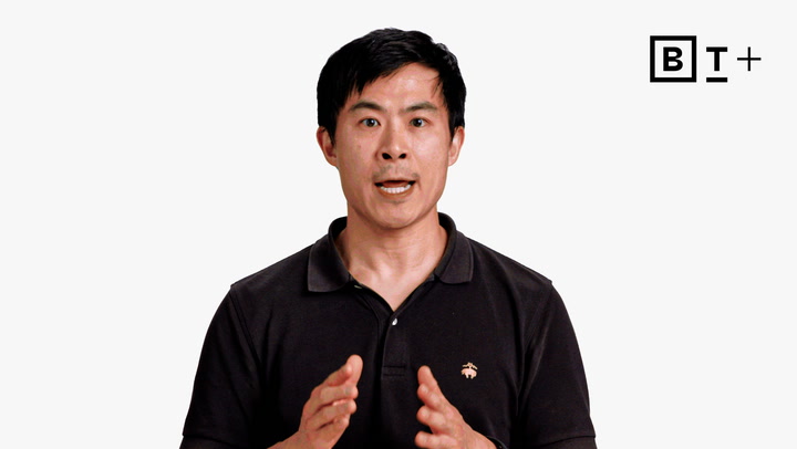 A man in a black polo shirt speaks while gesturing with his hands; a "B T+" logo appears in the top right corner against a plain white background.