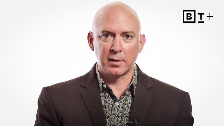 Bald man in a patterned shirt and dark blazer looks at the camera; BT+ logo appears in the top right corner on a white background.