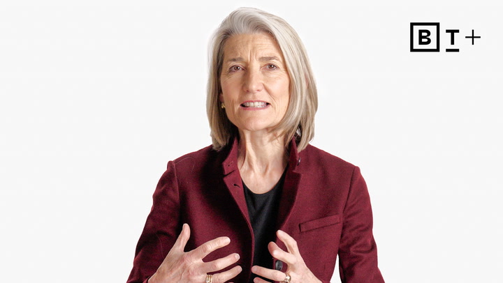 A woman with gray hair wearing a maroon blazer gestures with her hands while speaking, against a plain white background with a "BT+" logo in the corner.