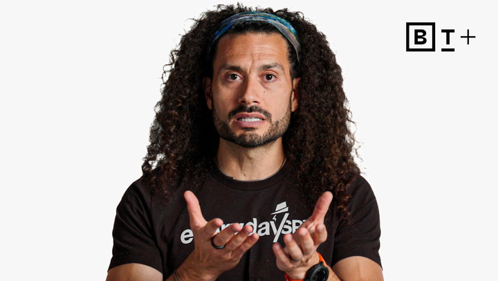 A man with long curly hair wearing a headband and a black t-shirt gestures with both hands while speaking; a BT+ logo is visible in the top right corner.