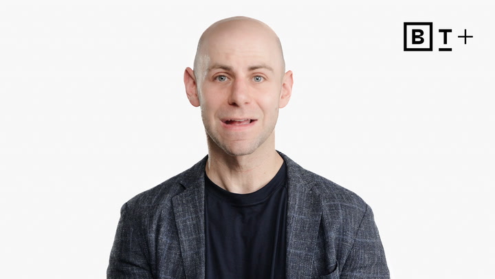 A bald man in a dark jacket and shirt stands in front of a white background with a "BT+" logo in the top right corner.