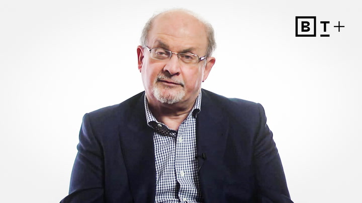 A middle-aged man with glasses and a beard, wearing a checkered shirt and dark blazer, sits against a plain white background with a "BT+" logo in the top right corner.