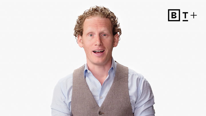 A man with curly hair wearing a light blue shirt and beige vest speaks in front of a white background with the BT+ logo in the top right corner.