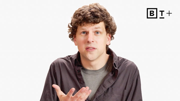 A man with curly hair wearing a dark button-up shirt gestures with one hand. There is a "B T +" logo in the top right corner on a white background.