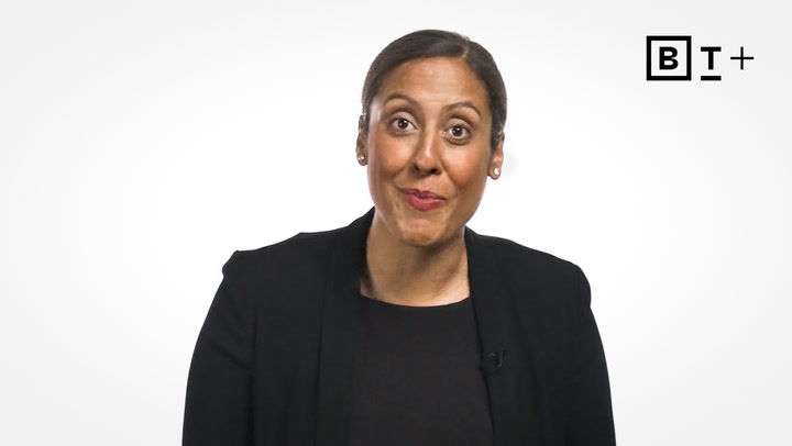 A woman in a black blazer and top stands against a plain white background with a "B T+" logo in the top right corner.