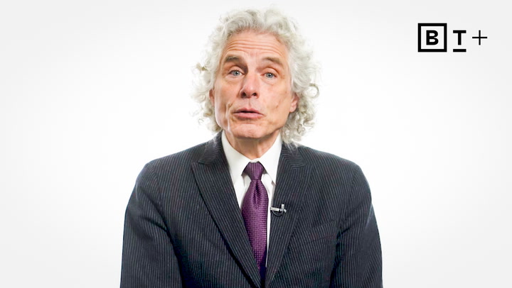 A man with curly gray hair in a suit and tie sits against a white background. A "BT+" logo is visible in the top right corner.