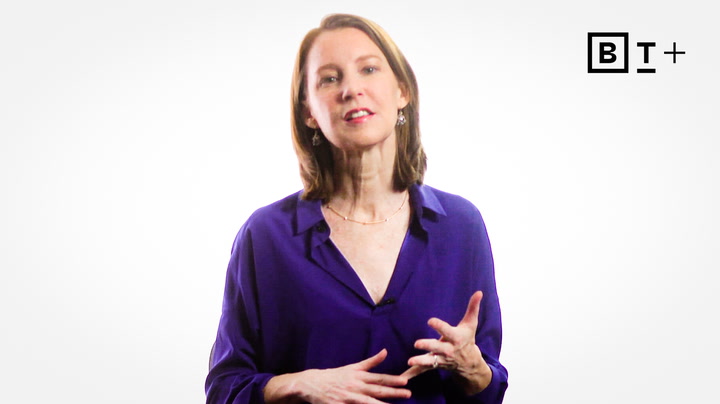 A woman in a purple blouse speaks while gesturing with her hands against a plain white background with a "BT+" logo in the corner.