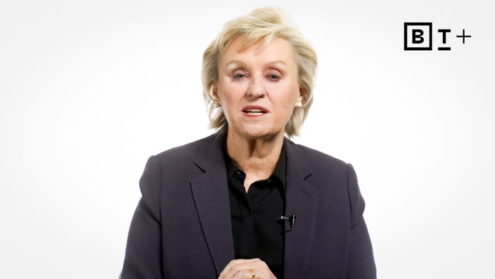 A woman with short blonde hair wearing a dark blazer and black shirt speaks in front of a white background with a "BT+" logo in the top right corner.